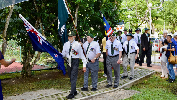New Zealand veterans marching with a NZ flag at a commemoration in Malaysia