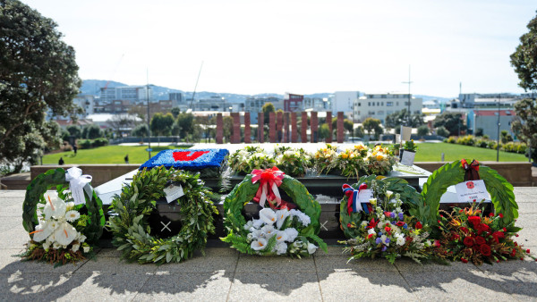 Five floral wreaths leaning against a concert and marble tomb.