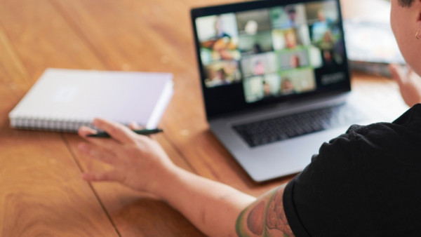 A person sitting at a table with a laptop and notebook