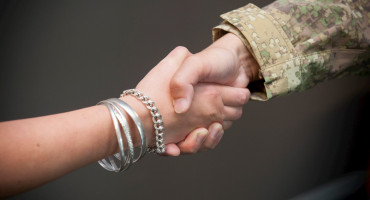 Two people shaking hands, one of them in uniform