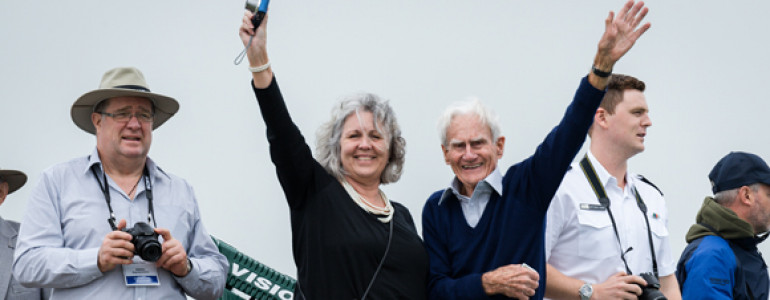 Two people looking happy wave to the camera