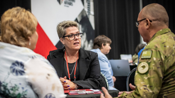 A woman who works for Veterans' Affairs speaking to a man in an Army uniform