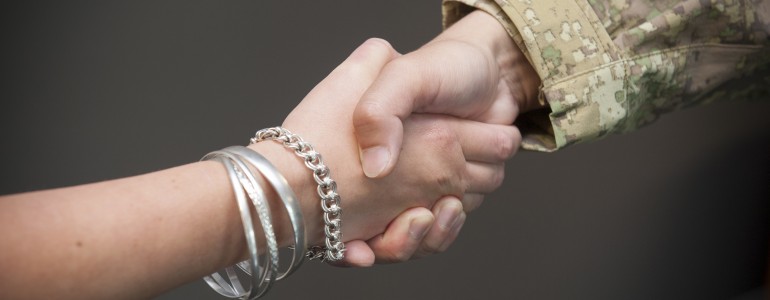 Two people shaking hands, one of them in uniform