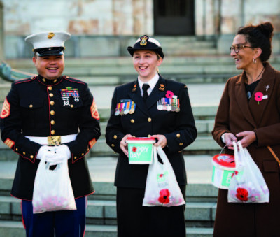 Two service people and a civilian selling poppies