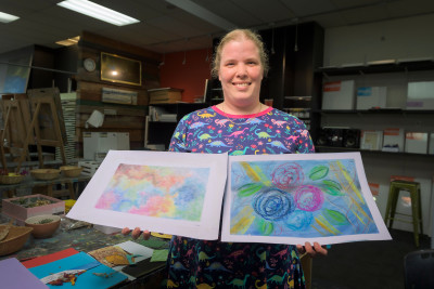 Gill McFarlane posing in an art studio with two paintings