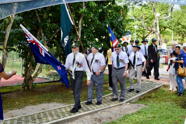 New Zealand veterans marching with a NZ flag at a commemoration. 