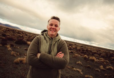 A smiling woman with her arms folded in tusok-filled desert