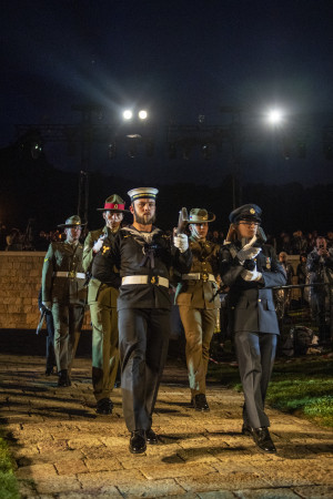 6 military personnel in different uniforms marching in slow time with ceremonial weapons