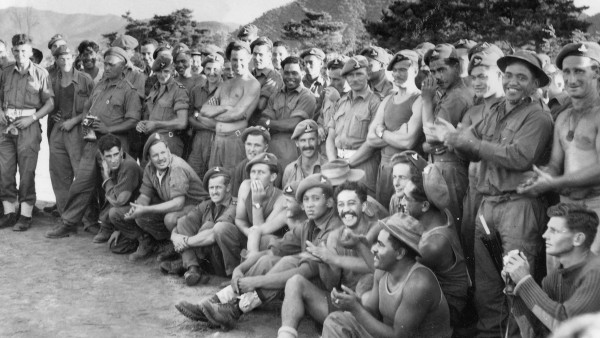 An old photo of 30 men in military uniform posing for the camera in Korean hillside