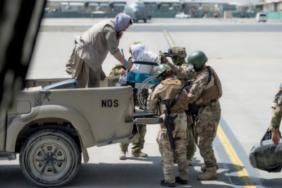 A woman in a wheelchair being lifted onto a pickup truck by soldiers at Kabul Airport Afghanistan