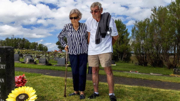 A man and woman stand at a memorial plaque