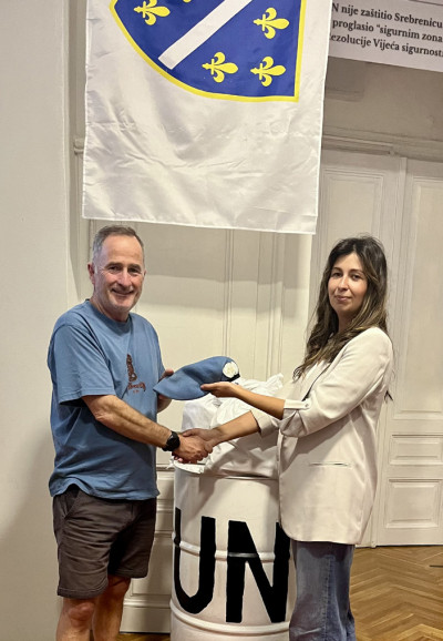A man and woman shaking hands as they exchange a beret