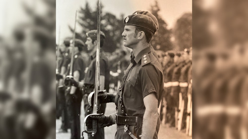 Richard Gray in uniform standing at attention with a ceremonial sword