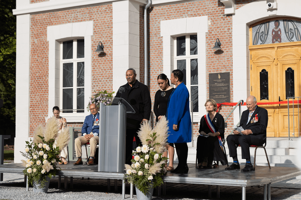 A man and two women standing at a podium in front of a the new brick museum