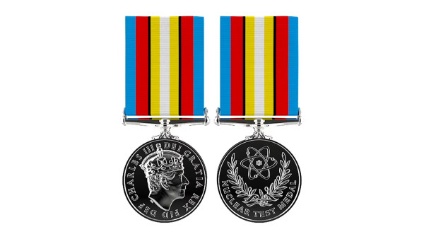The front of the medal, showing a profile image of King Charles on one side, and an atom surrounded by olive branches on the other 