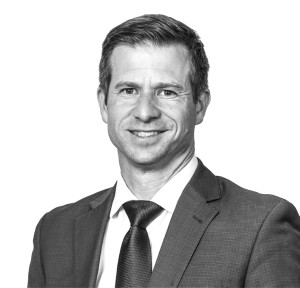 A headshot of a smiling man in a navy suit